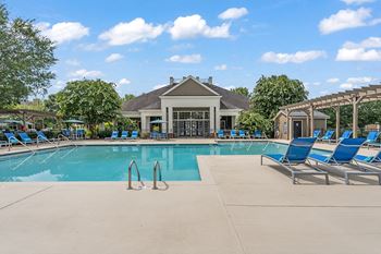 A resort style pool with lounge chairs and a clubhouse in the background